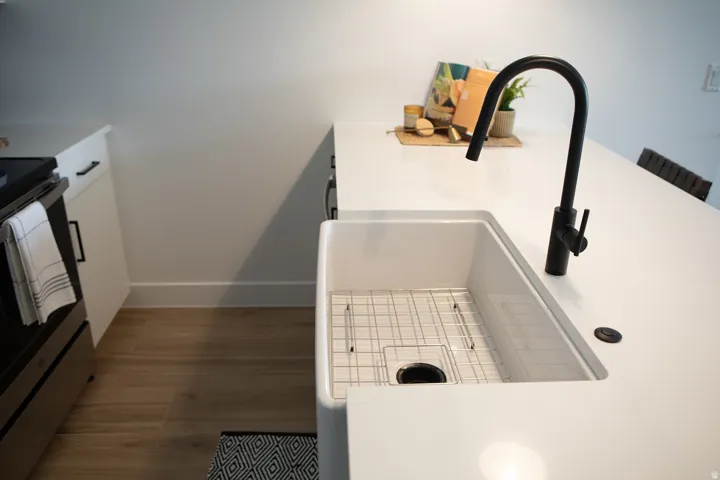 Kitchen view of white cabinetry, stainless steel electric stove, dark wood-style flooring, light countertops, and a kitchen bar