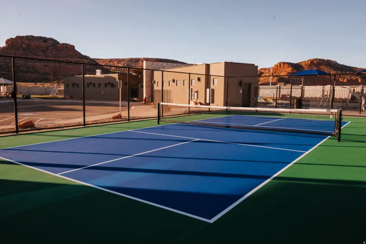 View of tennis court with community basketball court and a mountain view
