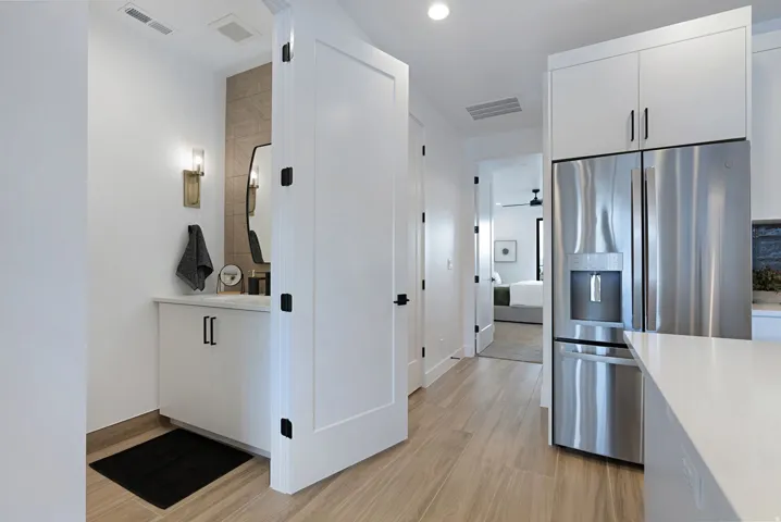 Kitchen featuring stainless steel fridge, white cabinets, light wood-style floors, light stone counters, and recessed lighting