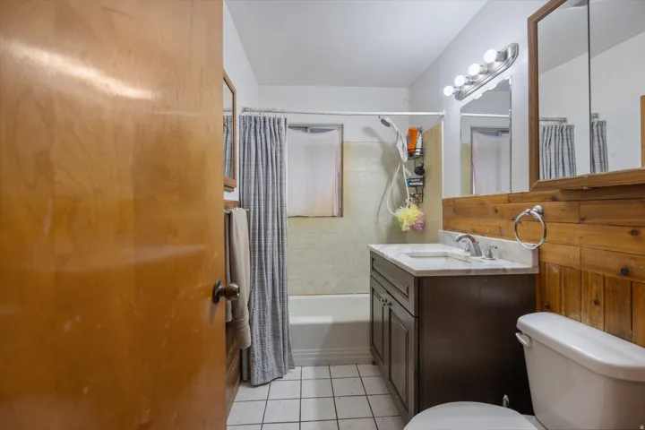 Bathroom featuring vanity, shower / bath combo with shower curtain, and light tile patterned floors