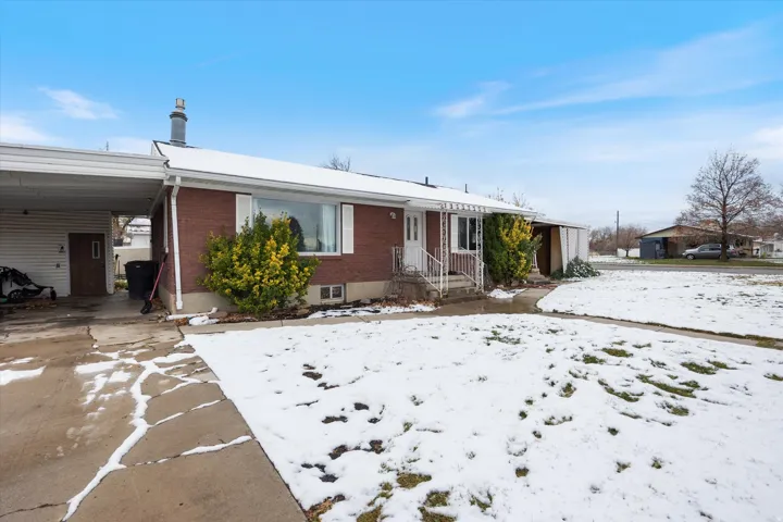 View of front of house featuring brick siding, an attached carport, and driveway