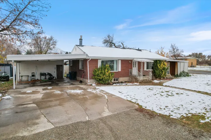 Ranch-style home with brick siding, concrete driveway, a carport, and a patio area