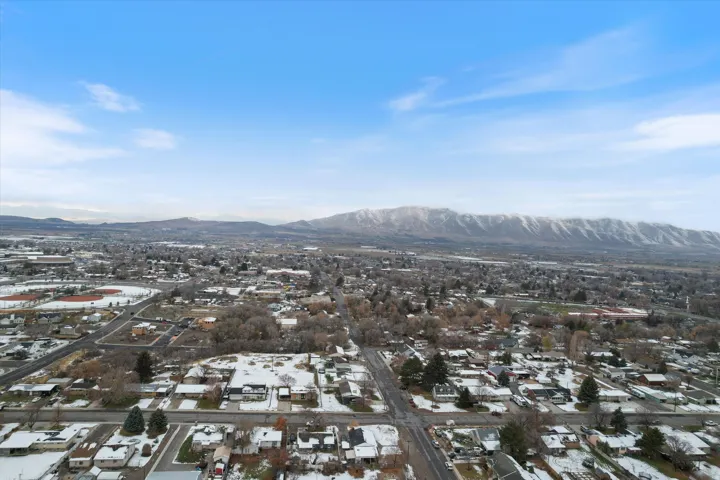 Snowy aerial view featuring a mountain view and a residential view