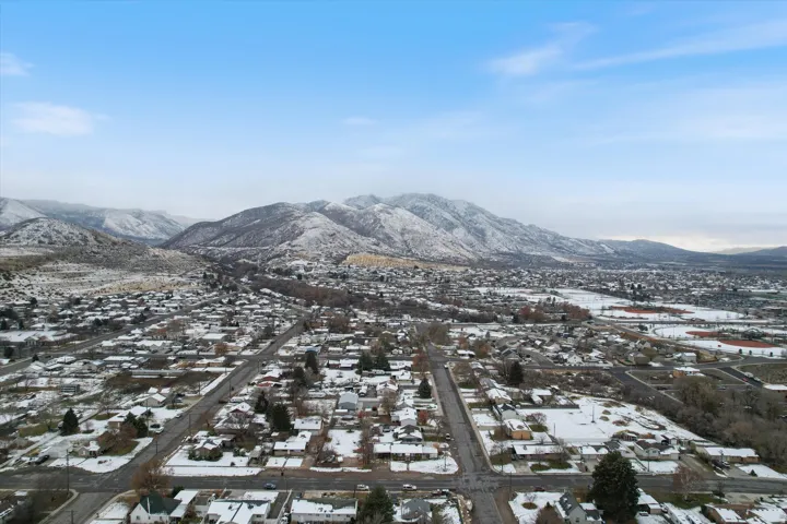 Snowy aerial view featuring a mountain view and a residential view