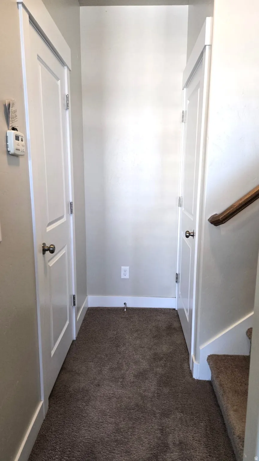 Corridor featuring dark carpet and baseboards