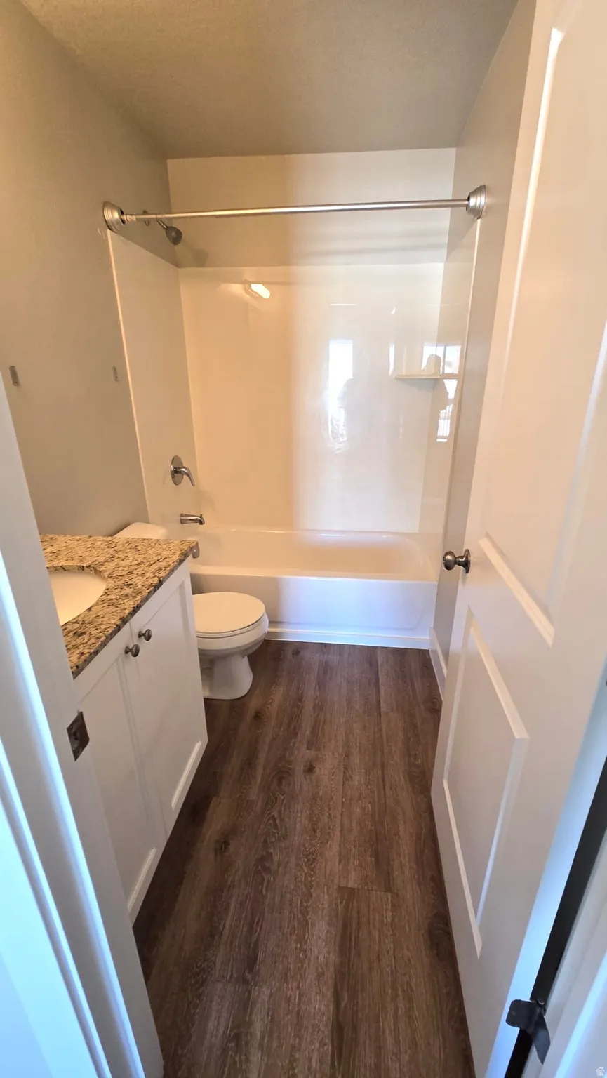 Full bathroom featuring vanity, shower / bathtub combination, dark wood finished floors, and a textured ceiling