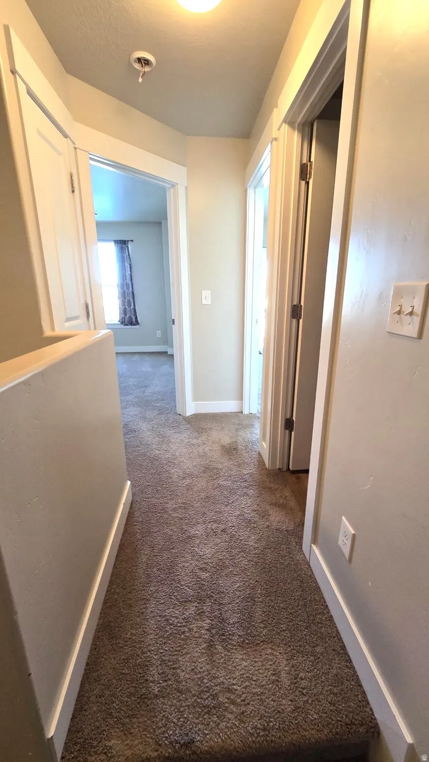 Corridor with carpet flooring and baseboards