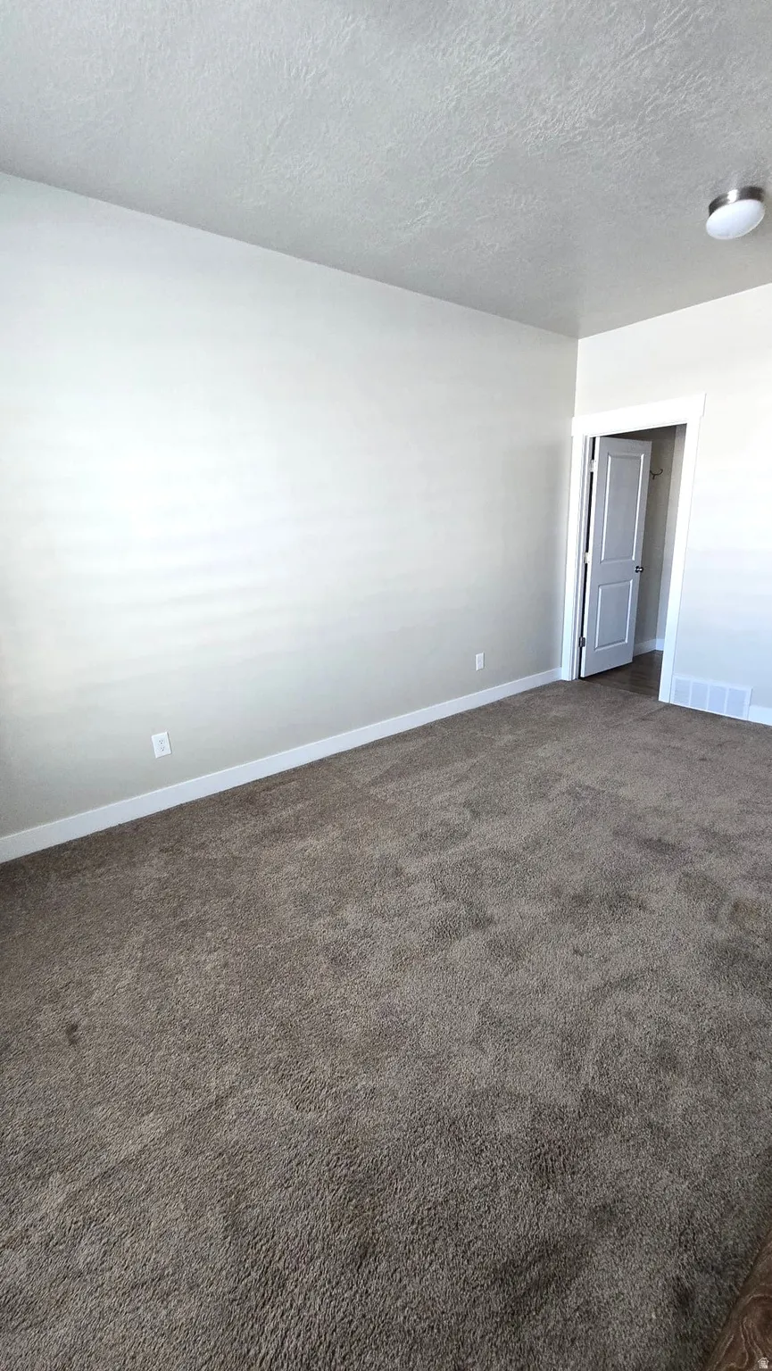Spare room with dark carpet and a textured ceiling