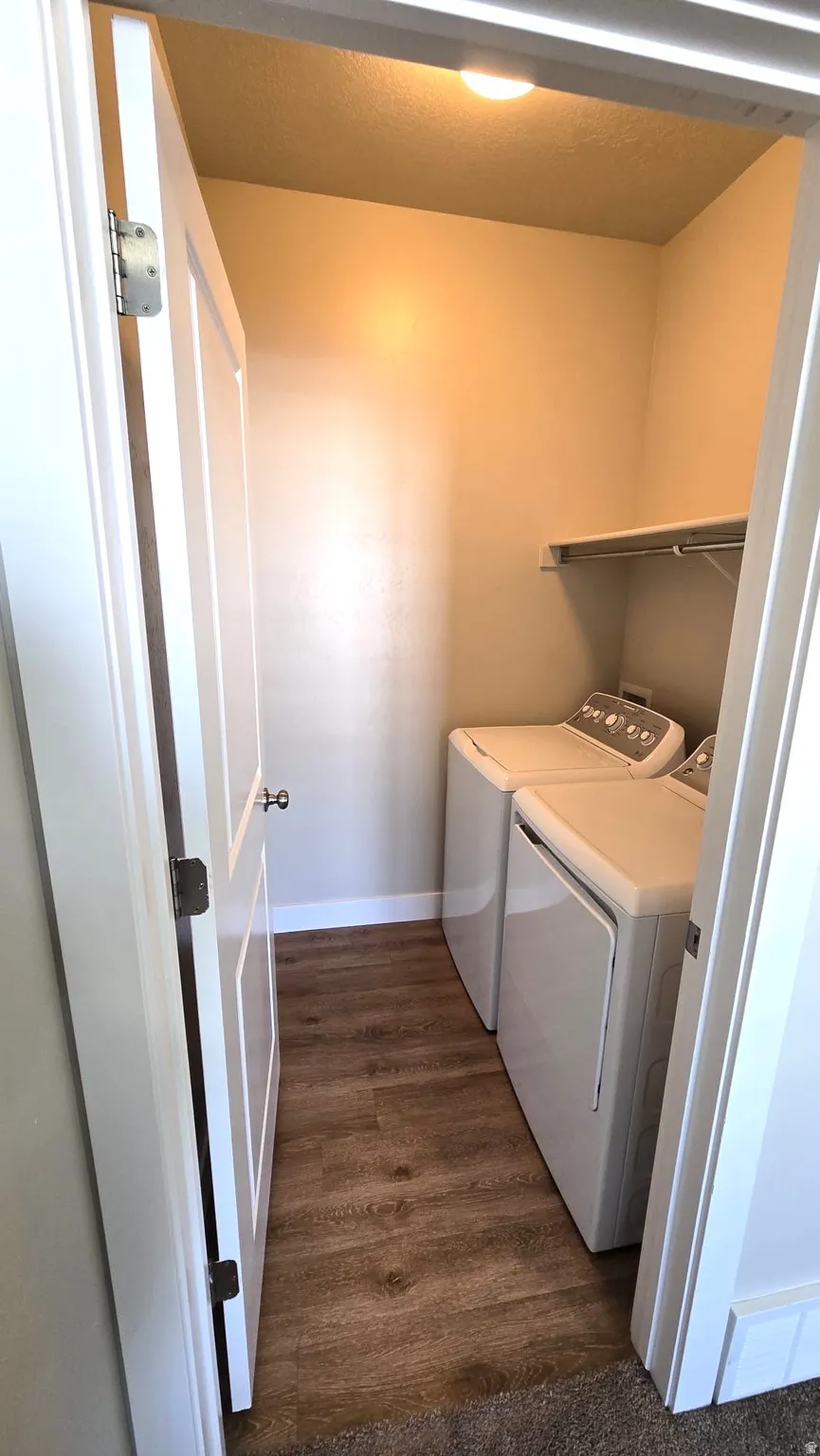 Laundry room featuring washer and dryer and dark wood-style floors