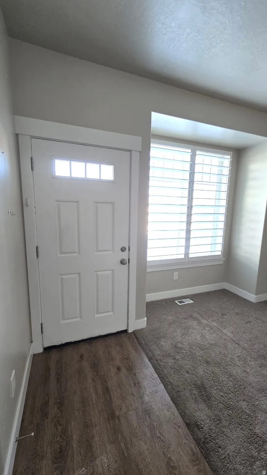 Foyer entrance featuring dark wood-type flooring and a textured ceiling