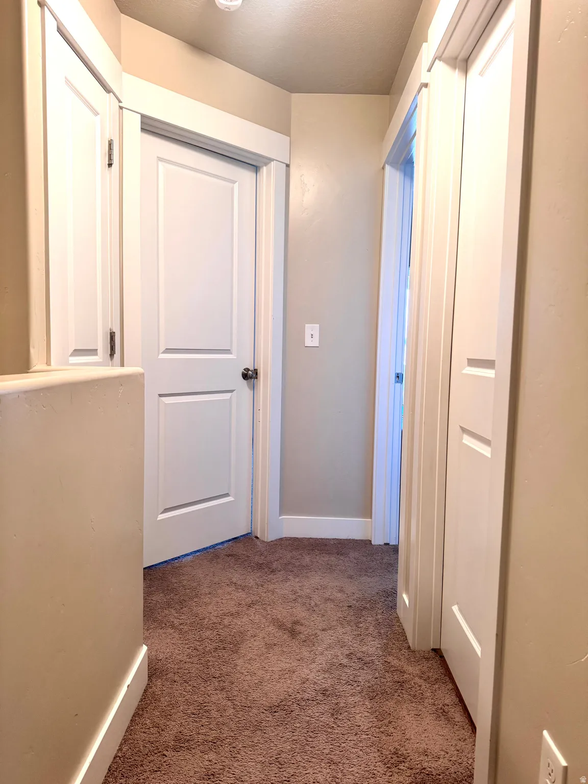 Hall featuring dark colored carpet and baseboards