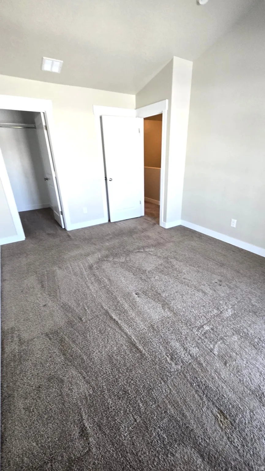 Unfurnished bedroom with a walk in closet and dark carpet