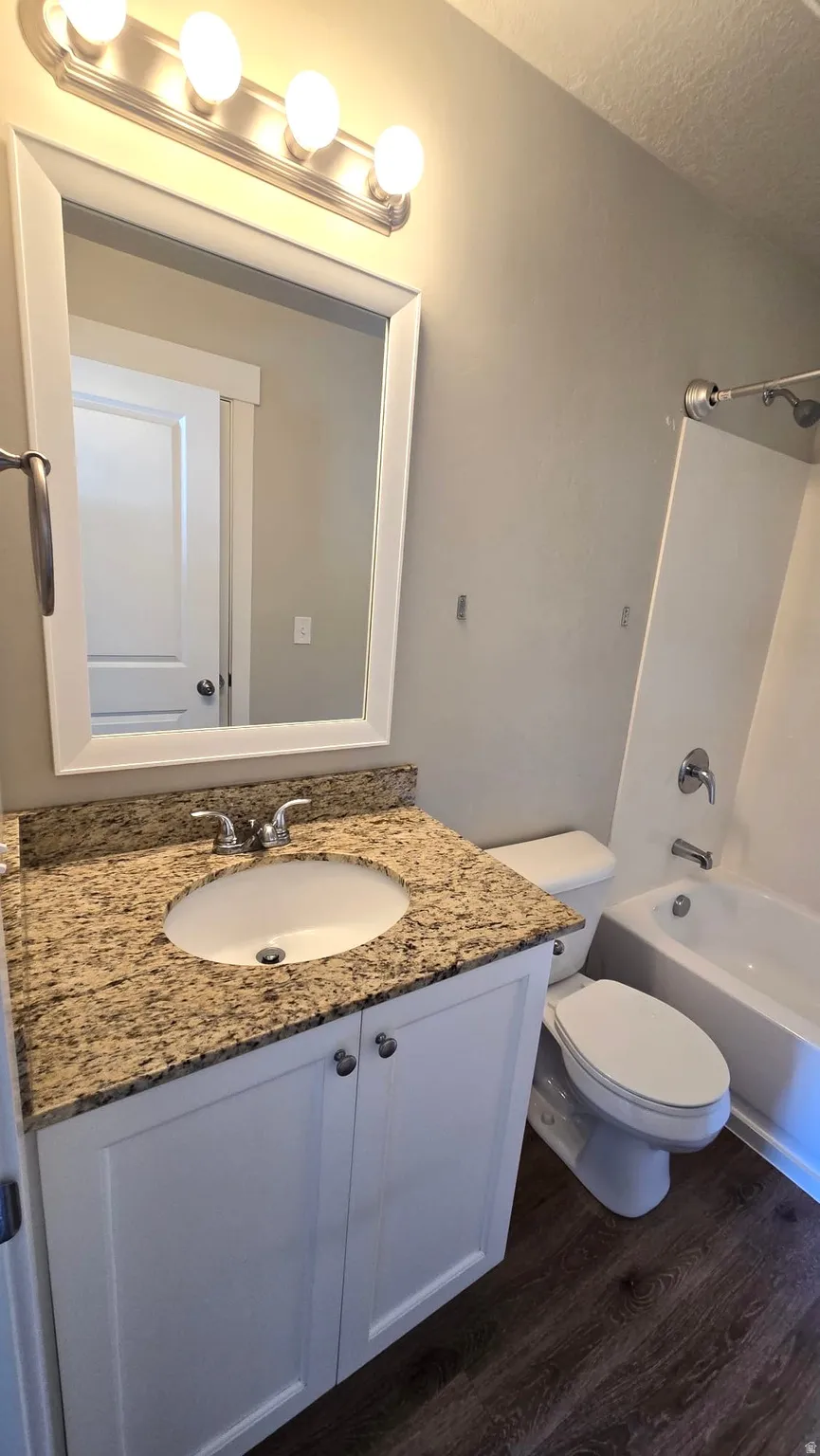 Full bathroom featuring vanity, tub / shower combination, and dark wood-type flooring