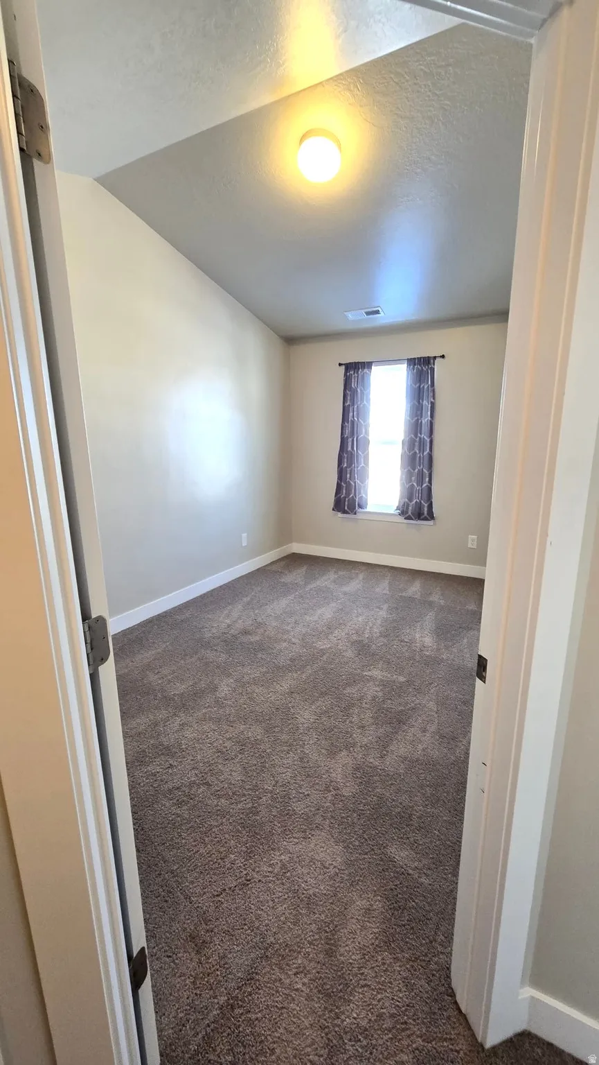 Empty room featuring dark colored carpet and a textured ceiling