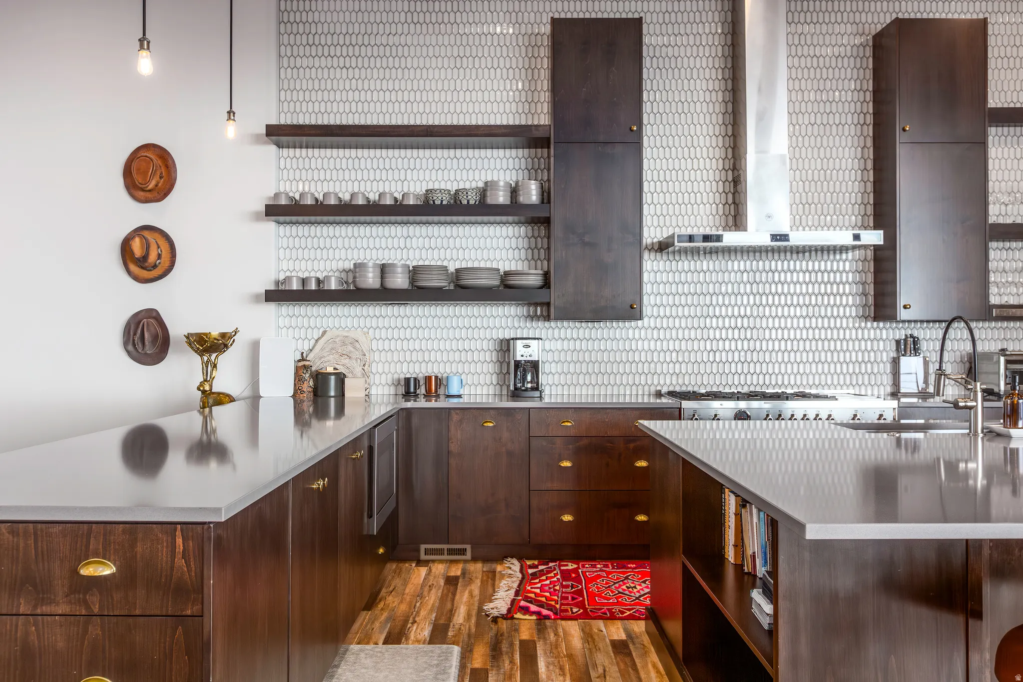 Kitchen with open shelves, wall chimney exhaust hood, dark brown cabinetry, a peninsula, and a kitchen bar