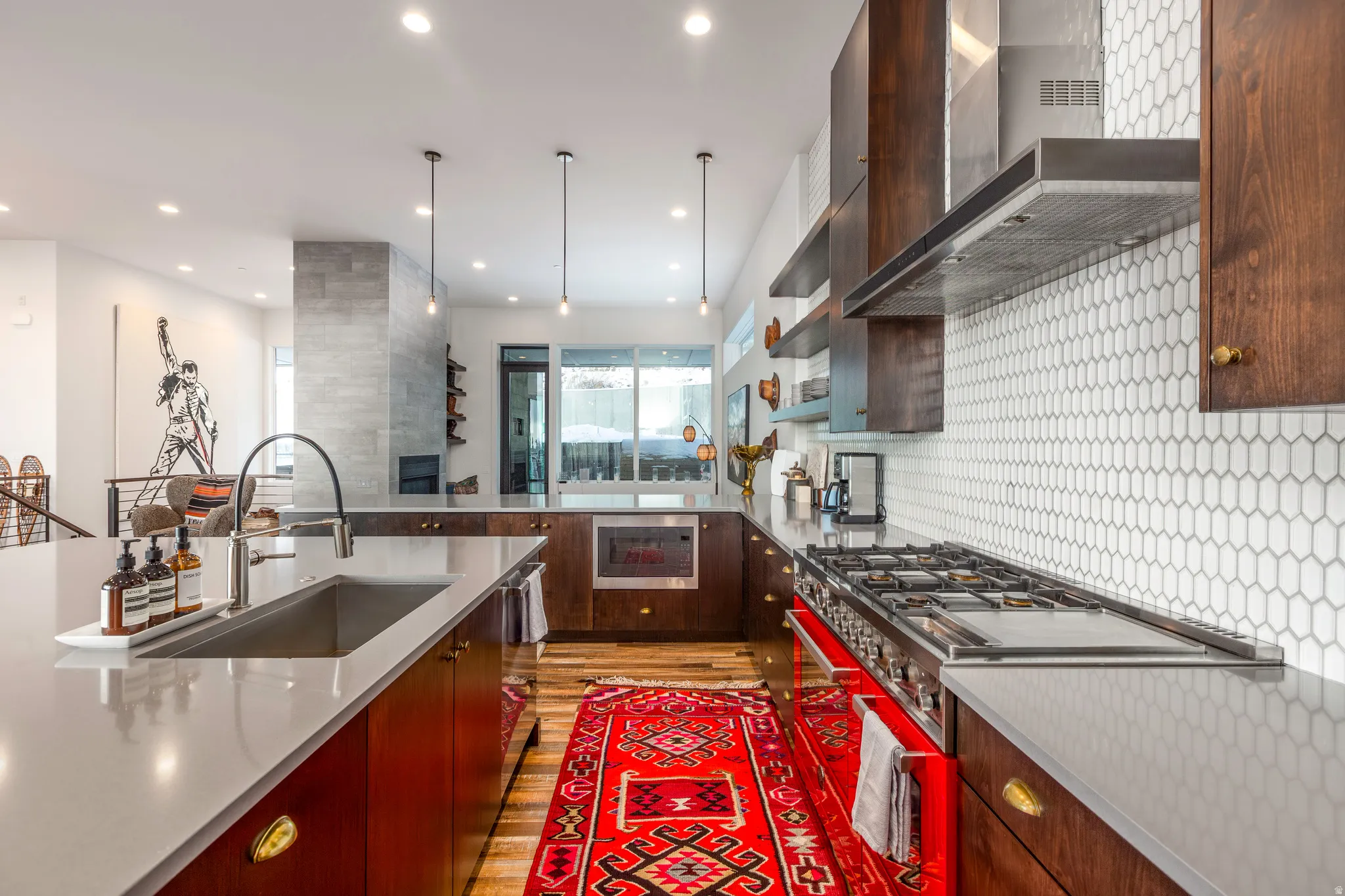 Kitchen with modern cabinets, wall chimney range hood, appliances with stainless steel finishes, light wood finished floors, and recessed lighting