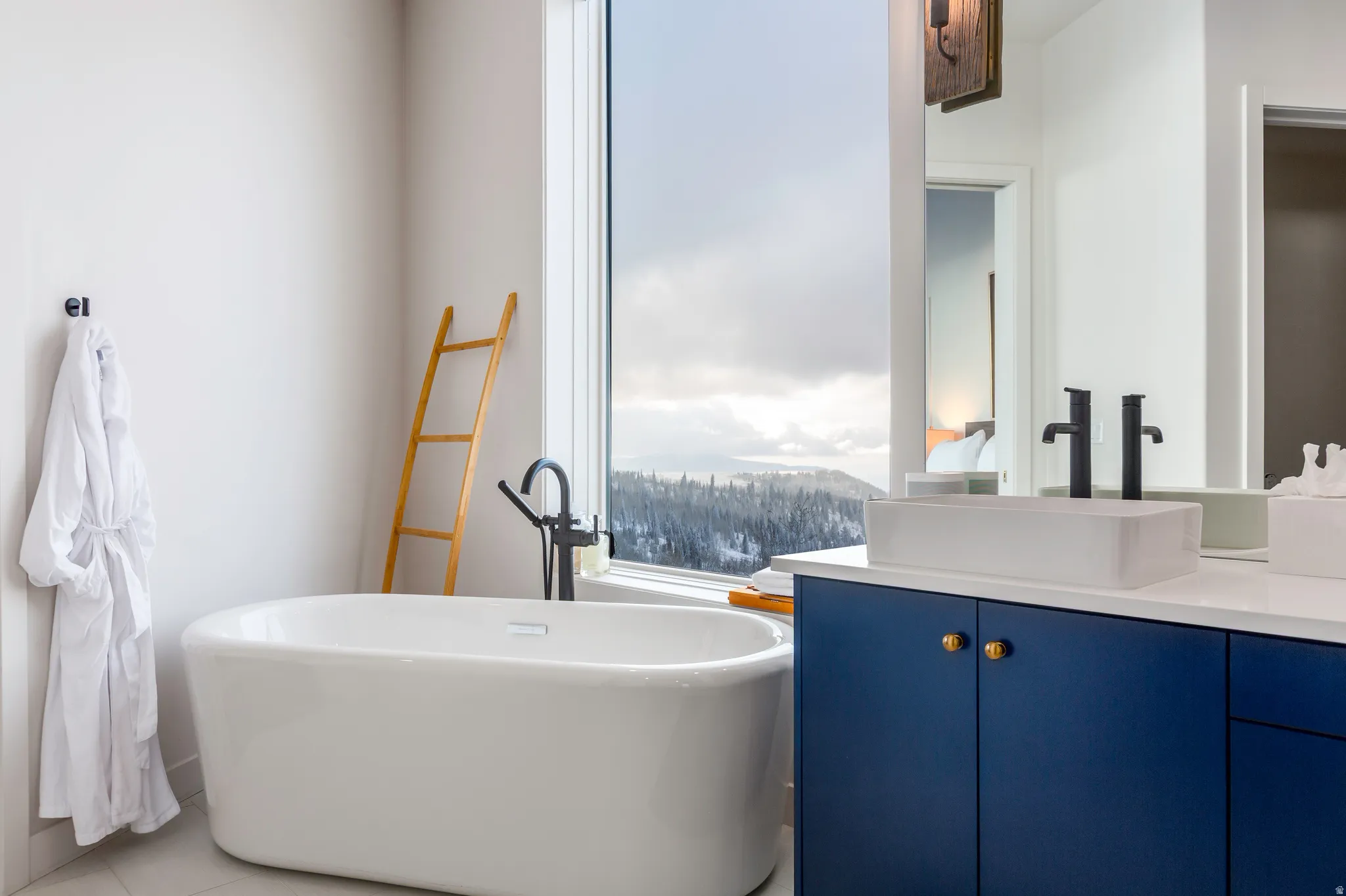 Full bathroom with vanity, a freestanding tub, and light tile patterned flooring