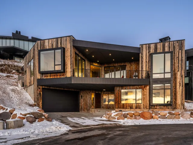 Modern home with a balcony, an attached garage, and driveway