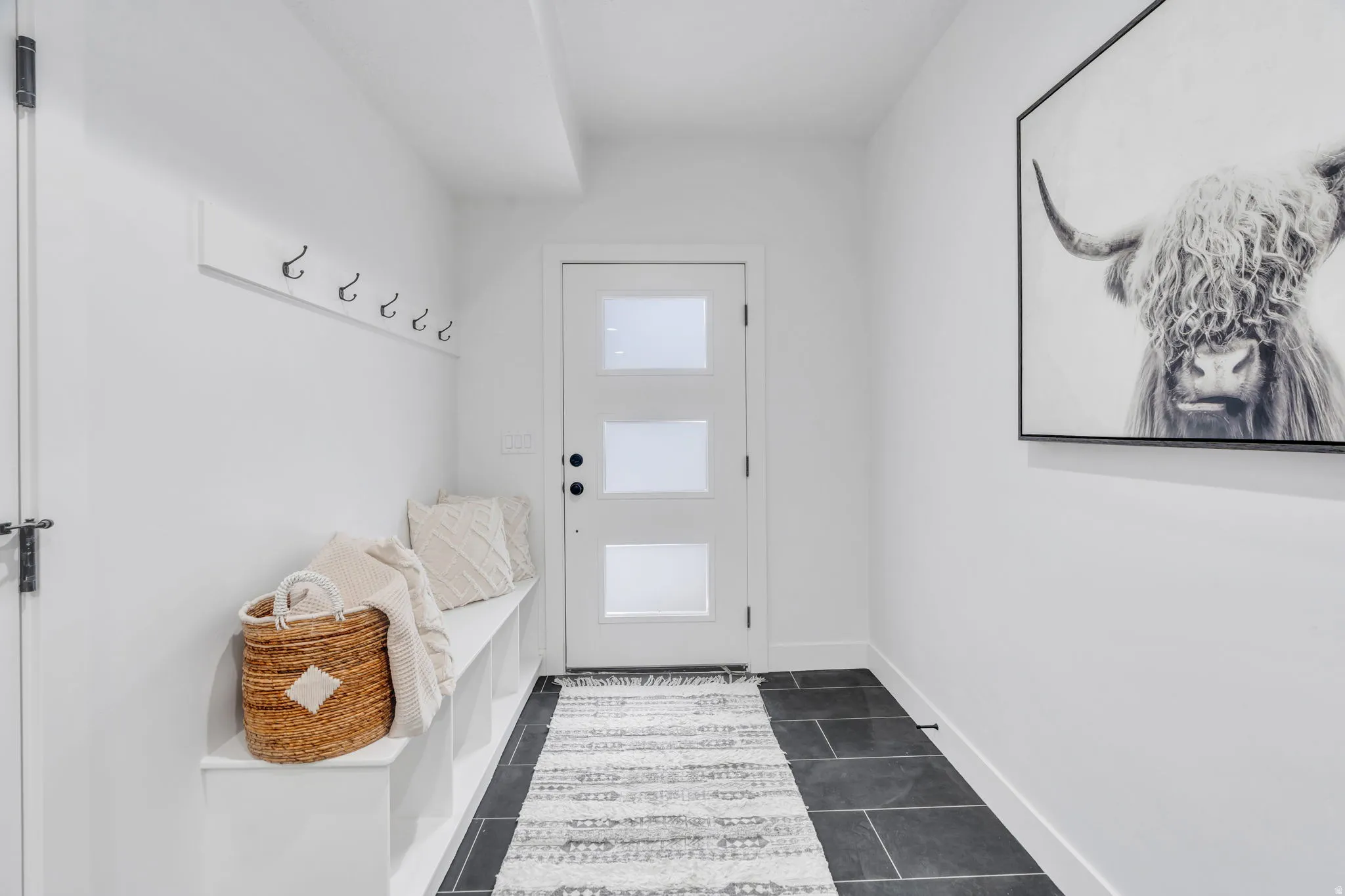 Mudroom featuring dark tile patterned flooring and baseboards