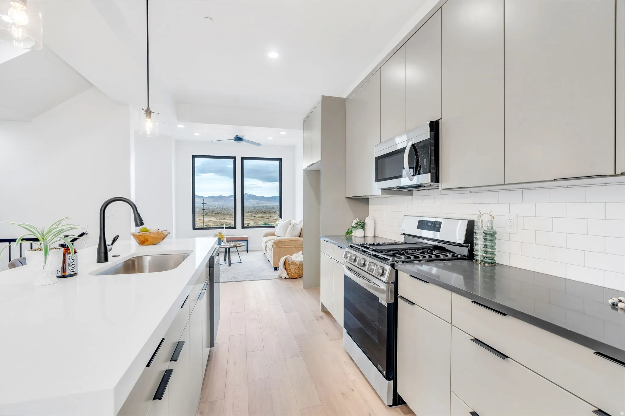 Kitchen featuring decorative light fixtures, appliances with stainless steel finishes, modern cabinets, light wood-style flooring, and open floor plan