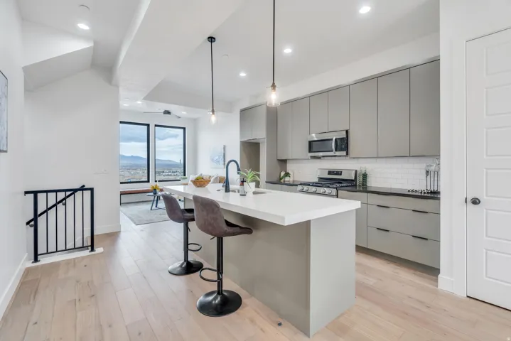 Kitchen featuring gray cabinets, an island with sink, modern cabinets, a breakfast bar, and stainless steel appliances