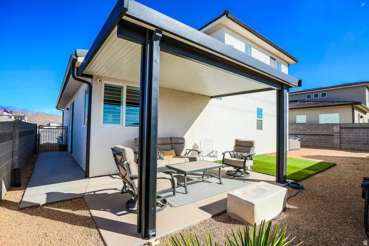 Back of house with outdoor lounge area, a patio, a gate, and stucco siding