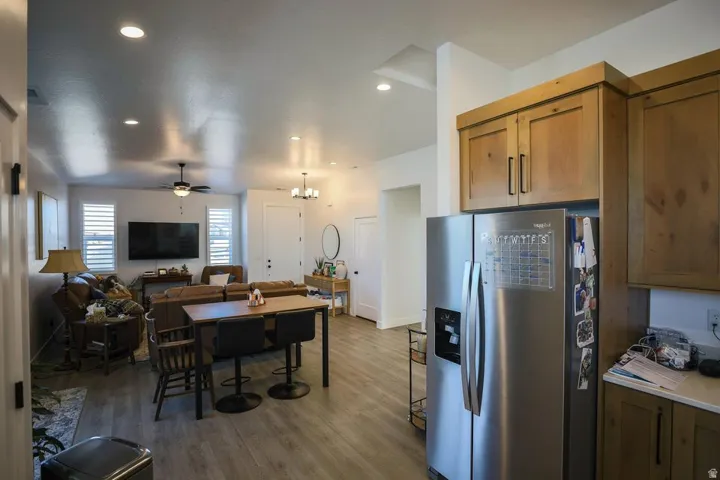 Kitchen with stainless steel fridge with ice dispenser, open floor plan, brown cabinetry, light wood-style flooring, and a chandelier