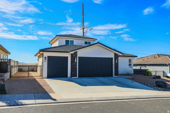 View of front of house with stucco siding, a tile roof, and driveway