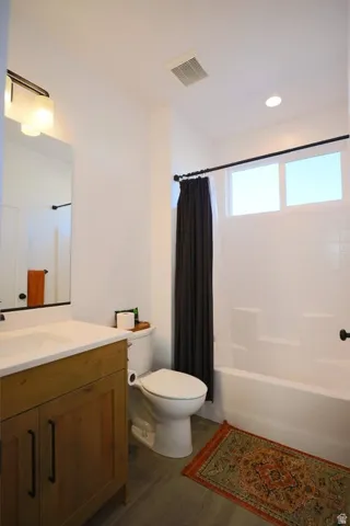 Full bath with dark wood-style flooring, shower / bath combination with curtain, vanity, and recessed lighting