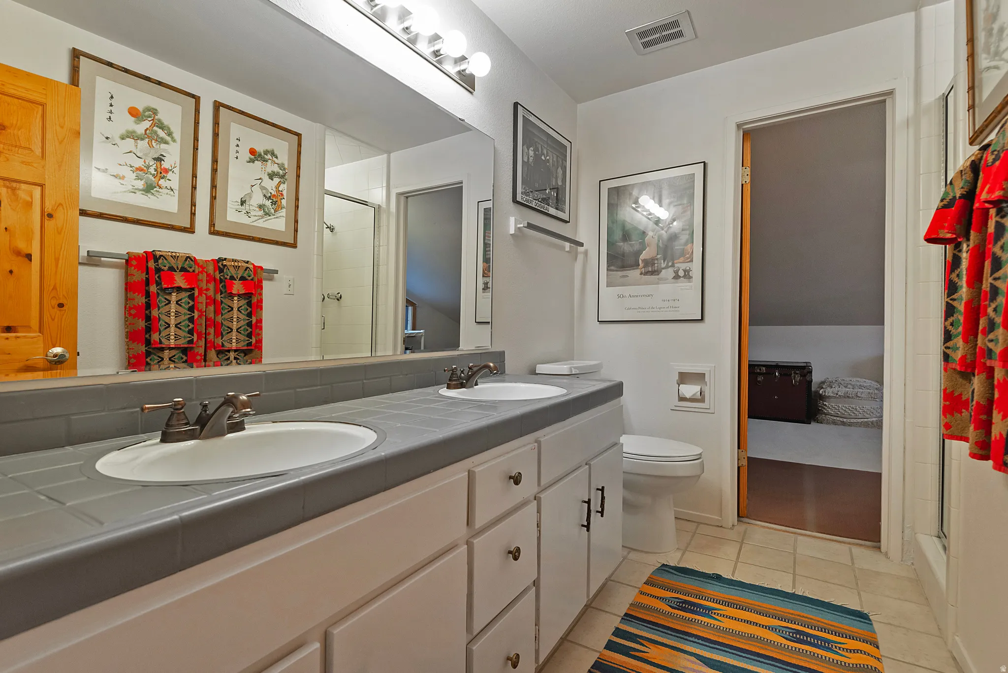 Bathroom featuring a stall shower, double vanity, and light tile patterned floors