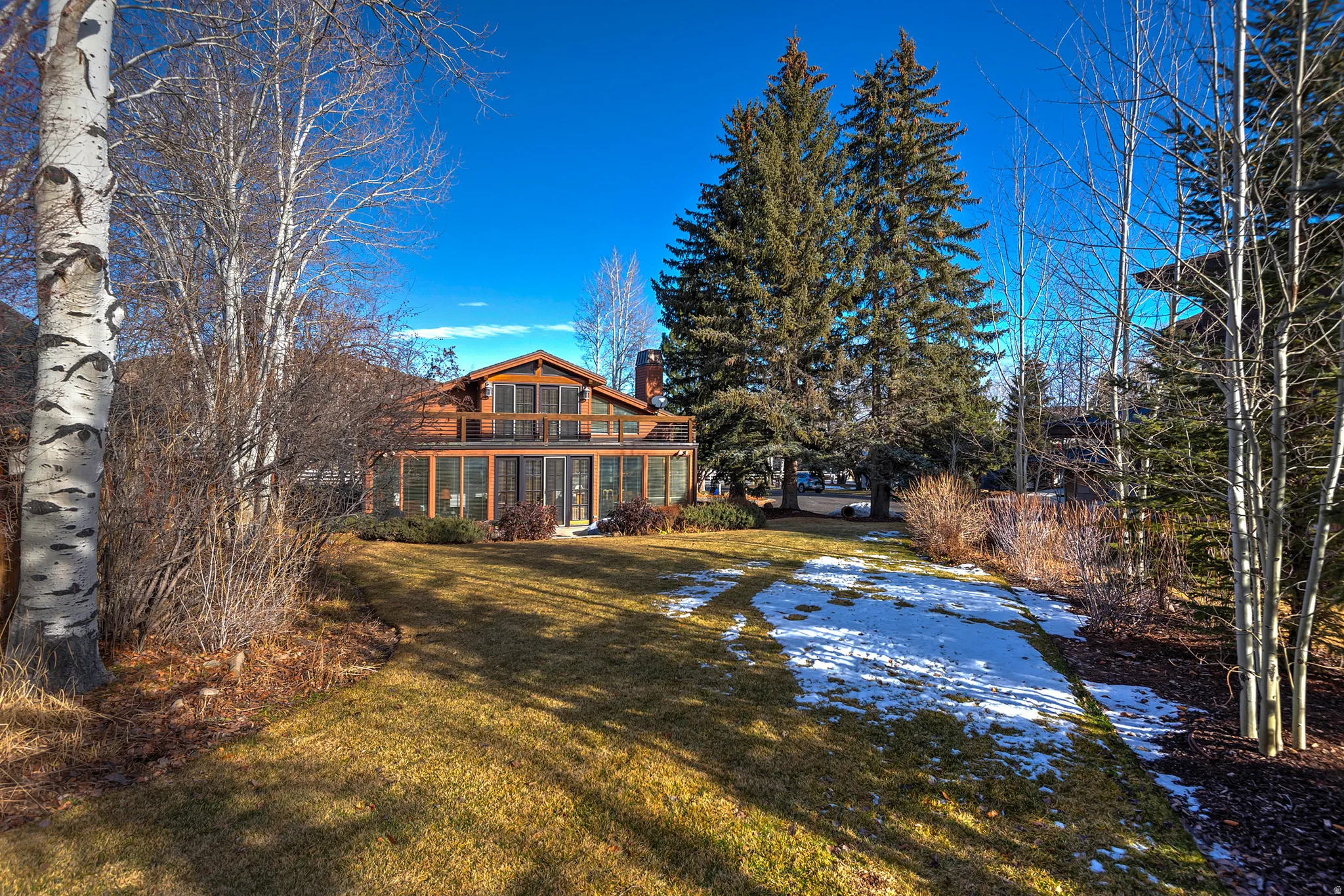 Back of property featuring a chimney, a lawn, and a porch