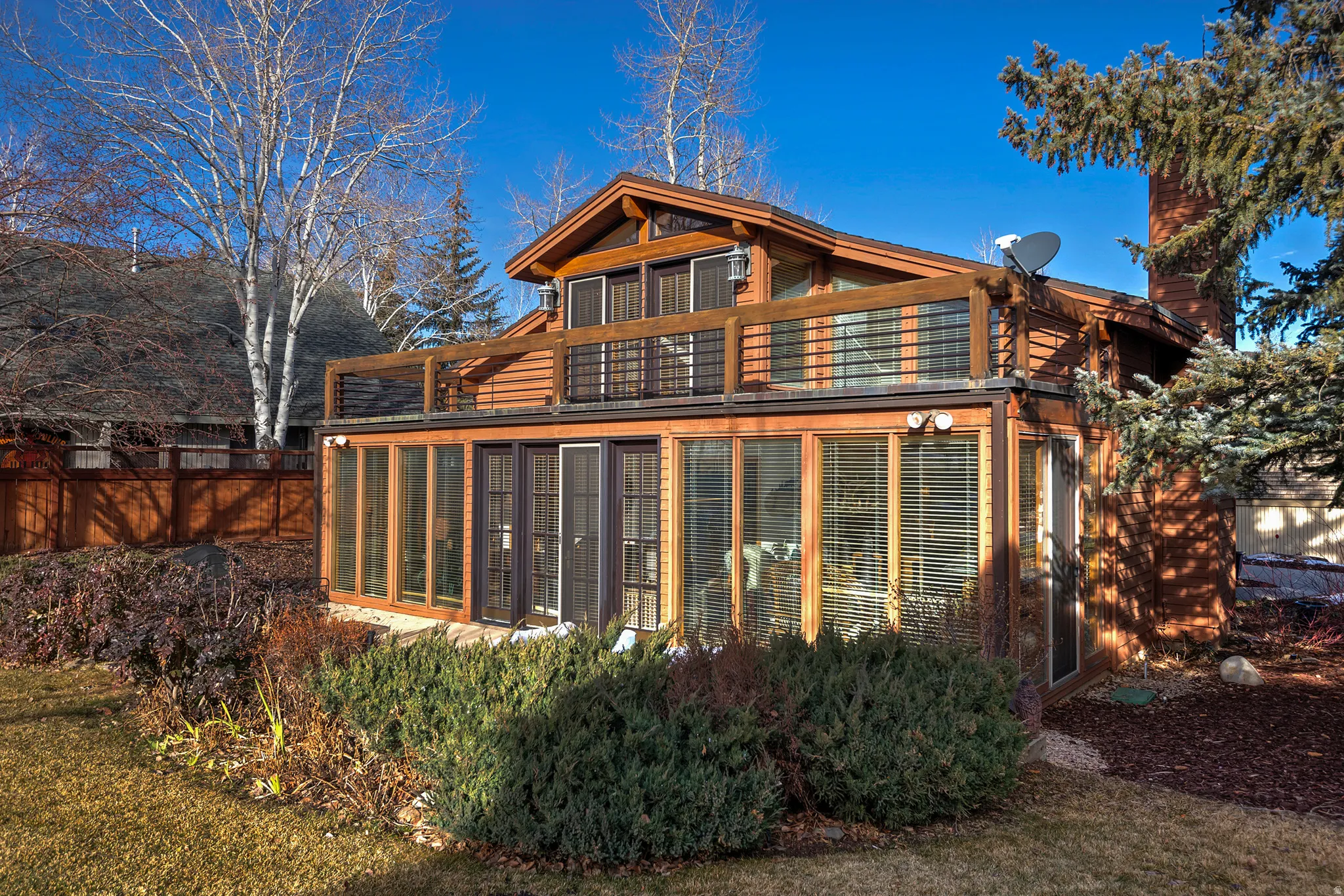 Back of property featuring a sunroom, a balcony, and a chimney