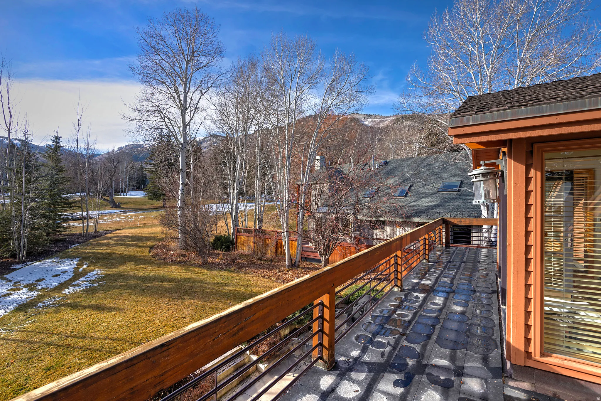 Snow covered deck with a yard, a balcony, and a mountain view