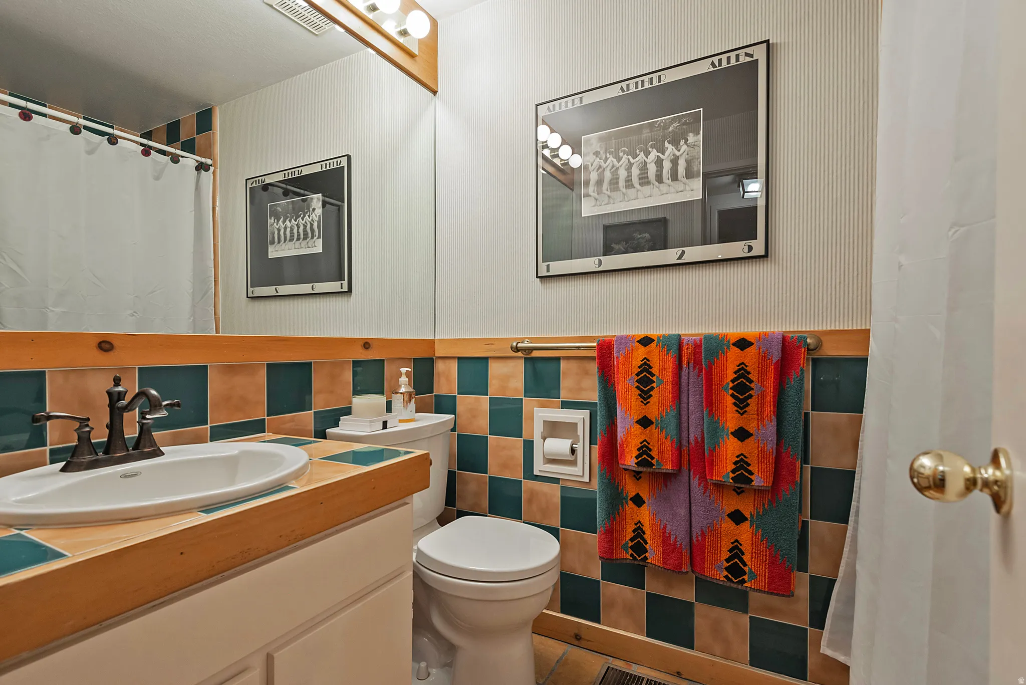 Full bathroom featuring a shower with shower curtain, vanity, tile walls, and wainscoting