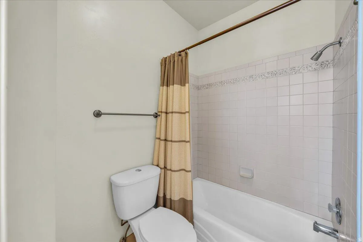 Bathroom featuring shower / bath combination with curtain and toilet