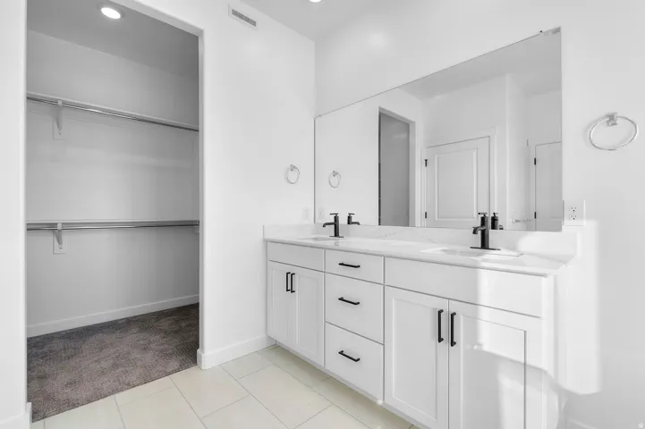 Full bathroom featuring double vanity, a spacious closet, recessed lighting, light colored carpet, and light tile patterned flooring
