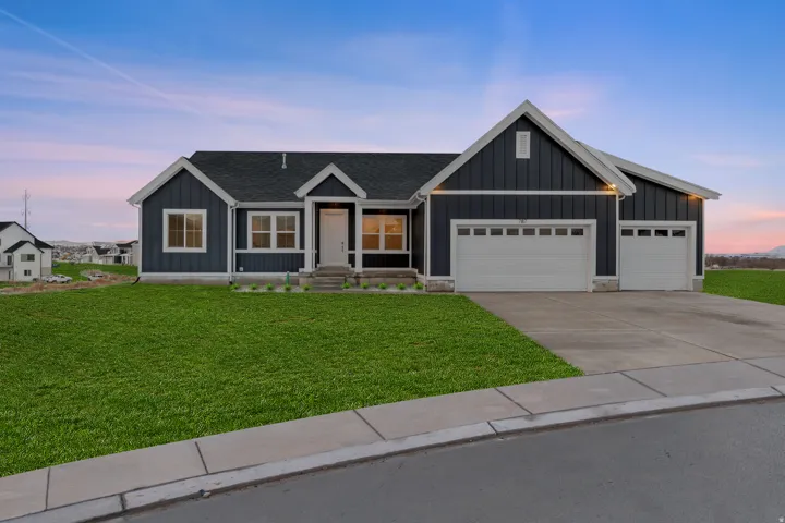 View of front of property featuring board and batten siding, concrete driveway, a yard, and a garage