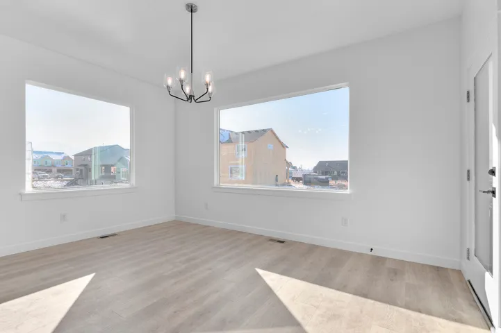 Unfurnished dining area featuring light wood finished floors and a chandelier