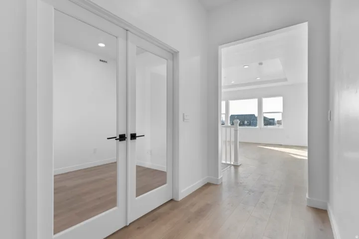 Hall with recessed lighting, light wood-style flooring, and a raised ceiling