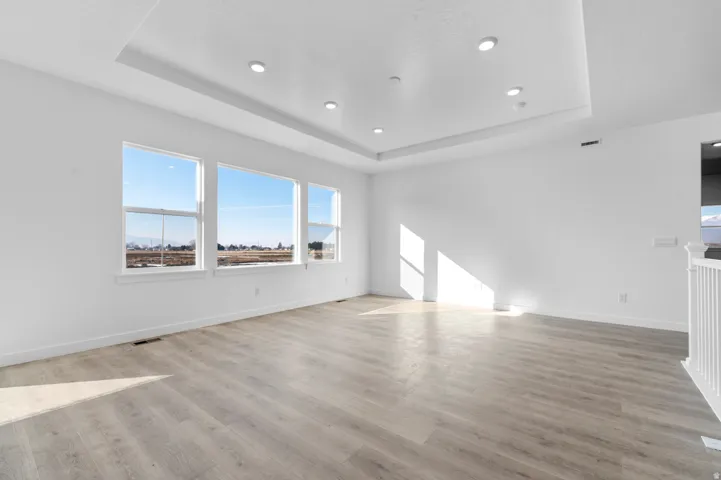 Unfurnished room with a raised ceiling, light wood finished floors, and recessed lighting