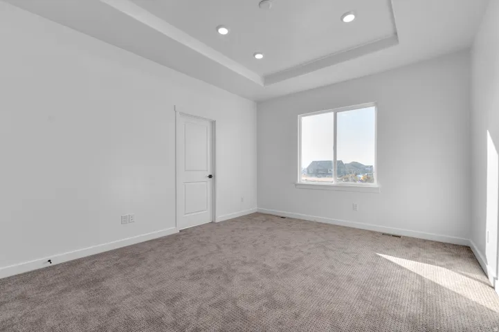 Carpeted empty room with a tray ceiling and recessed lighting