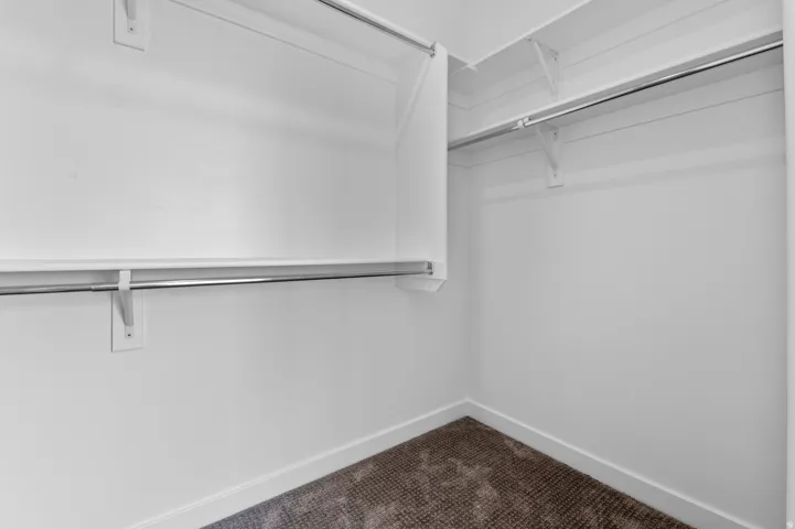 Walk in closet featuring dark carpet