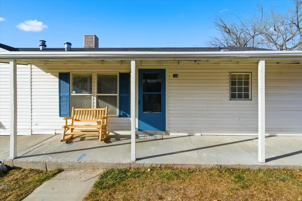 View of exterior entry with a porch and roof with shingles