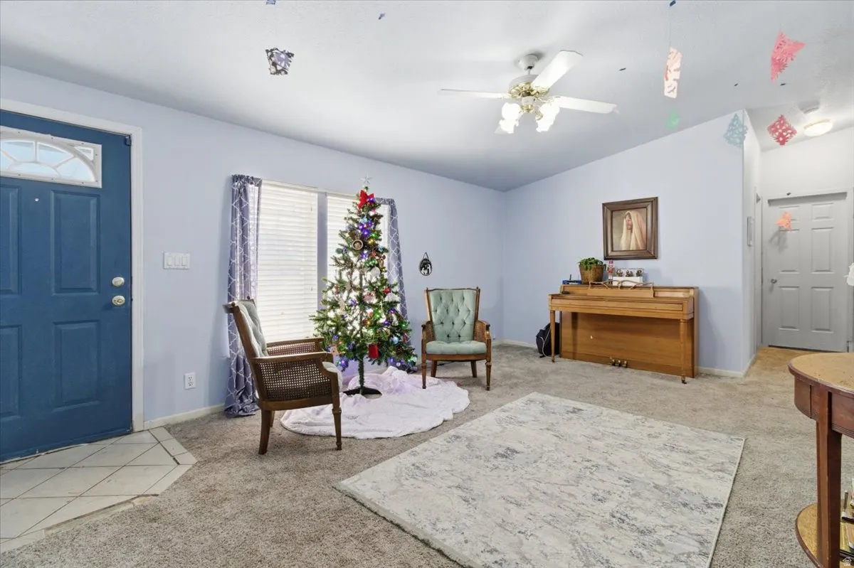 Foyer entrance featuring lofted ceiling, light colored carpet, and a ceiling fan