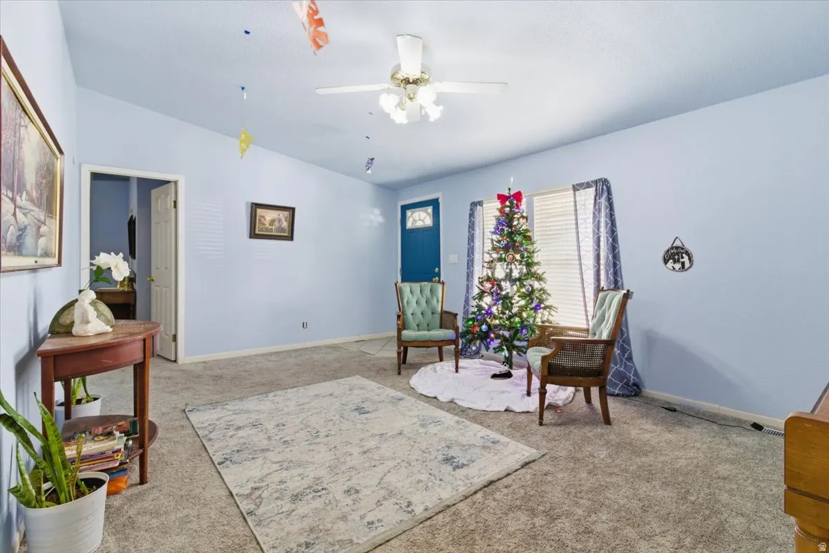 Living area featuring light colored carpet, ceiling fan, and lofted ceiling