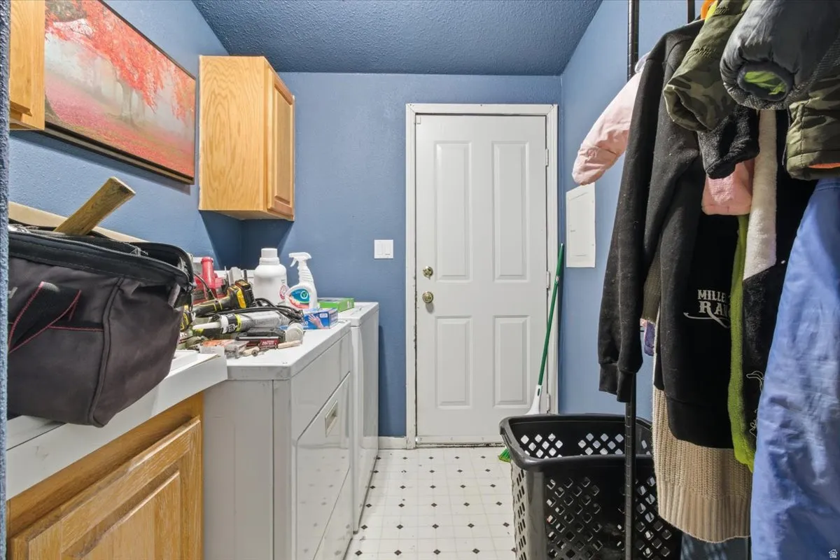Laundry area featuring light flooring, cabinet space, washer and dryer, and a textured ceiling