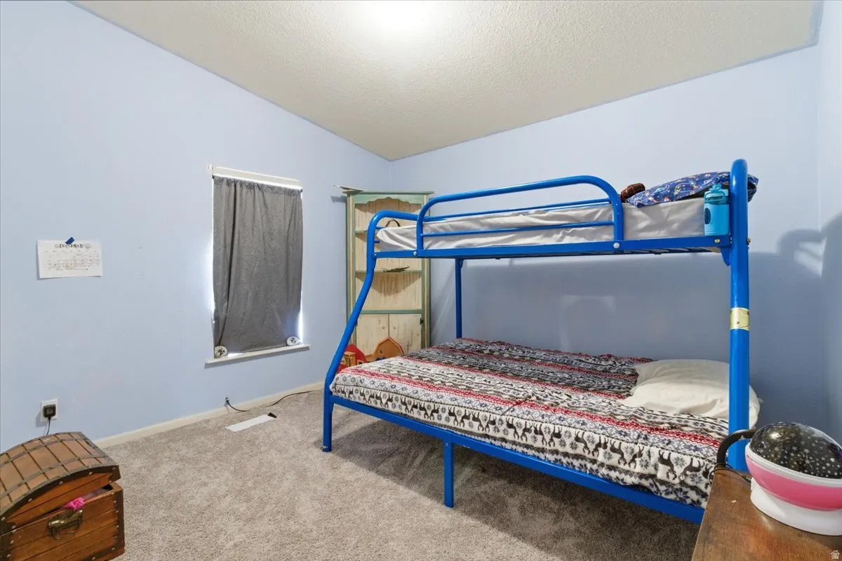 Bedroom featuring lofted ceiling, carpet flooring, and a textured ceiling
