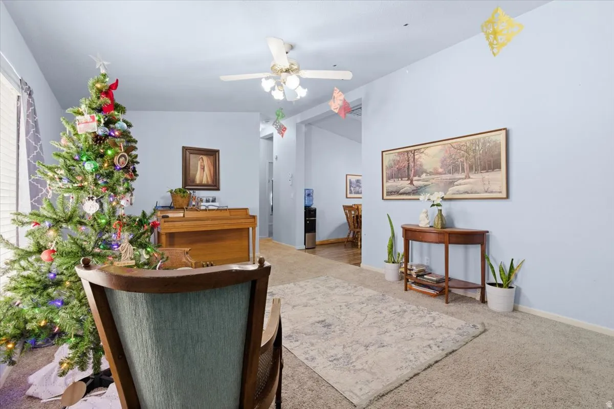 Living area with vaulted ceiling, carpet flooring, and a ceiling fan