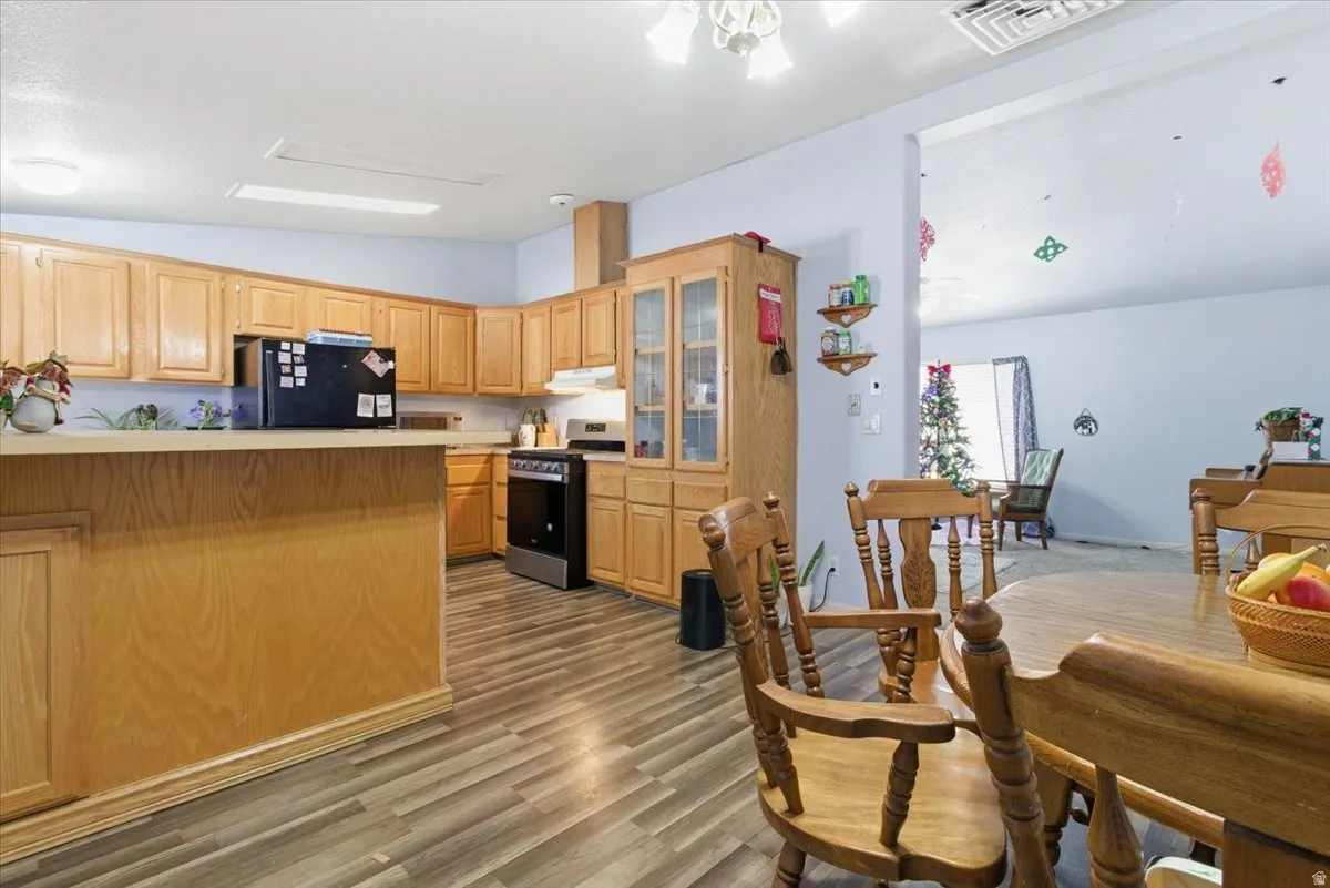 Kitchen featuring vaulted ceiling, light countertops, stainless steel gas range, glass insert cabinets, and light wood finished floors