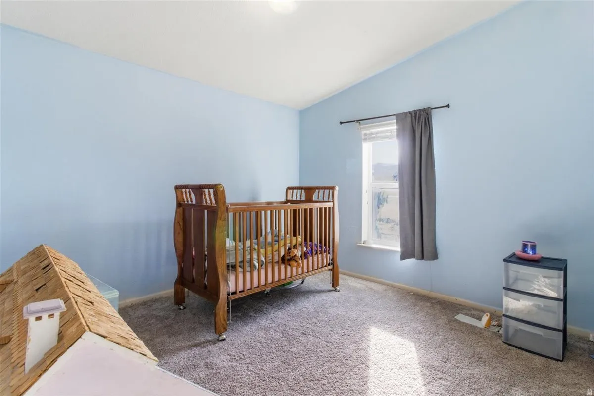 Bedroom with vaulted ceiling, carpet, and a nursery area